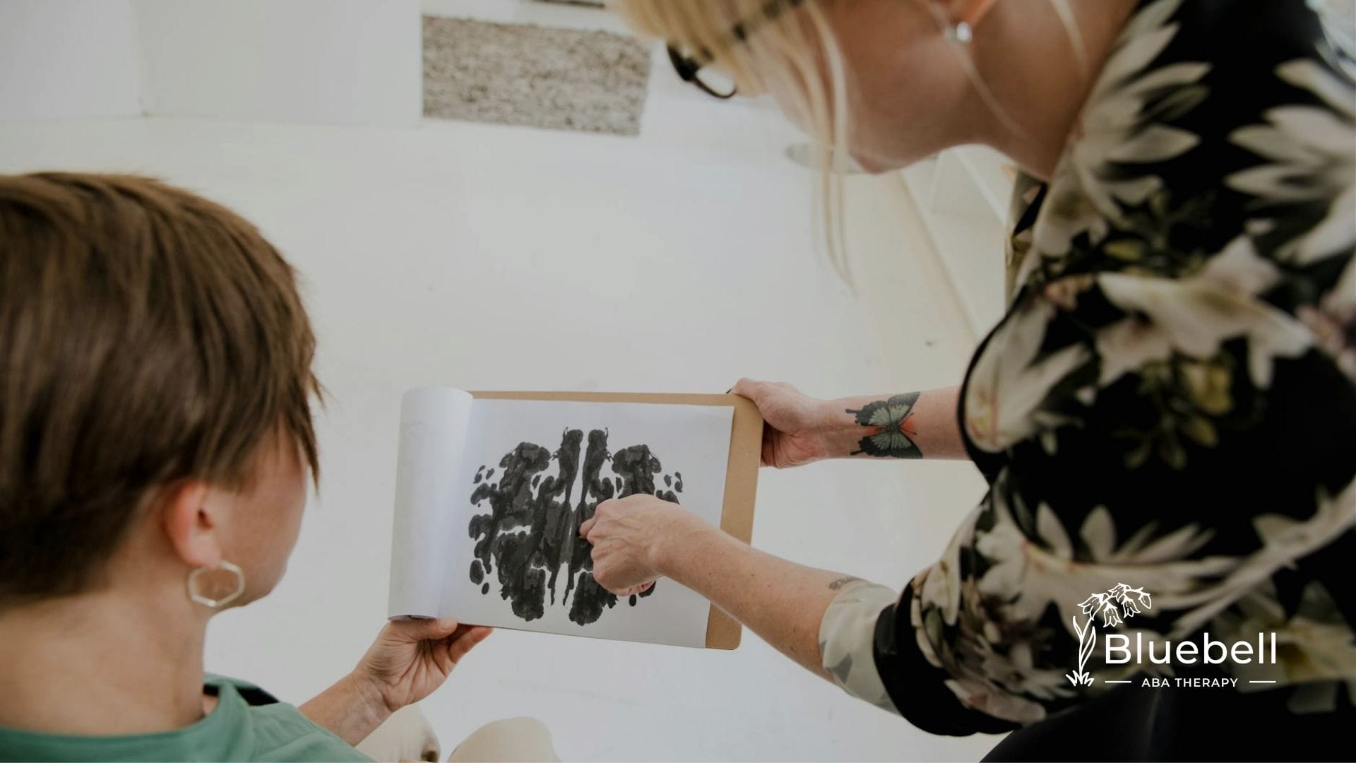 ABA therapist shows a Rorschach inkblot test to a seated client during a session in North Carolina.