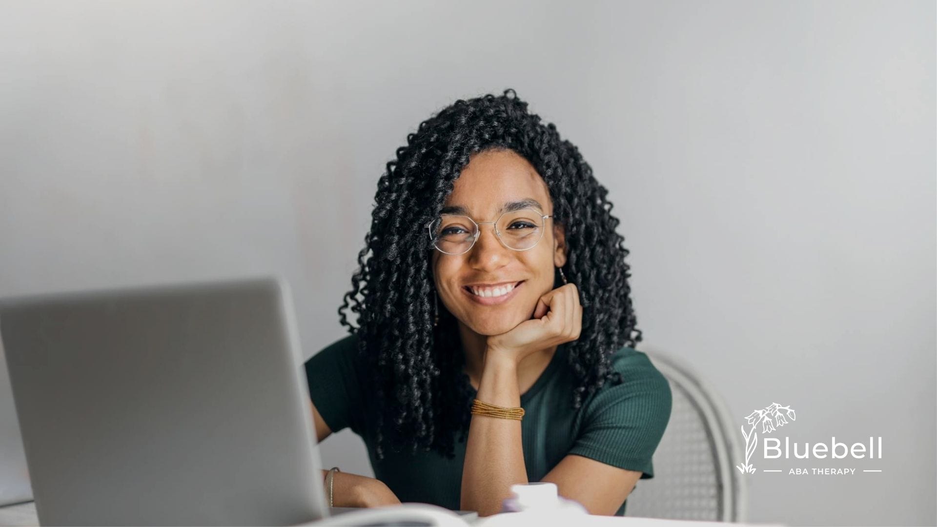 BCBA aspirant with curly hair and glasses studying on her laptop for BCBA exam in North Carolina.