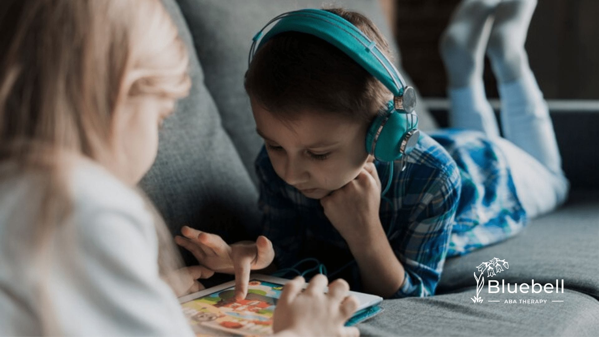 A kid wearing headphones playing with a tablet
