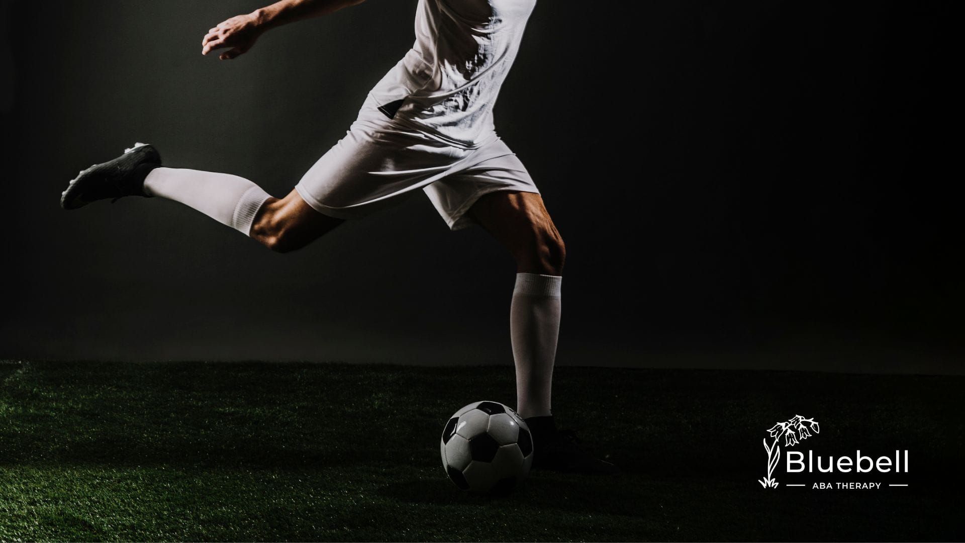 A professional footballer is kicking a football on a field