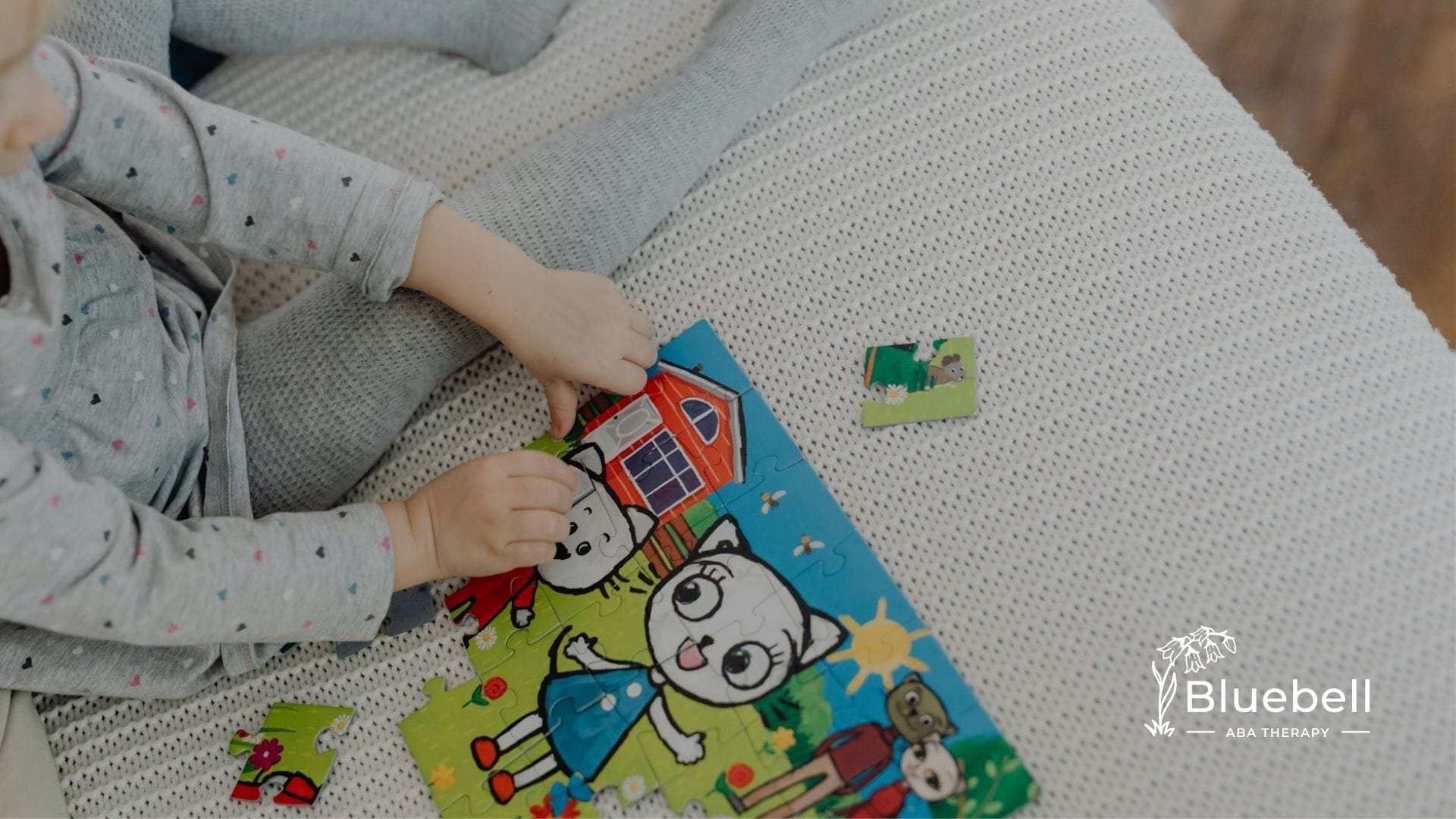 An autistic child assembling a puzzle featuring cartoon characters on a blanket in North Carolina.