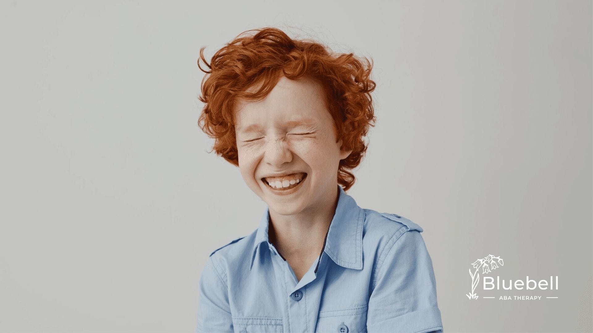 An autistic child smiling with his eyes closed