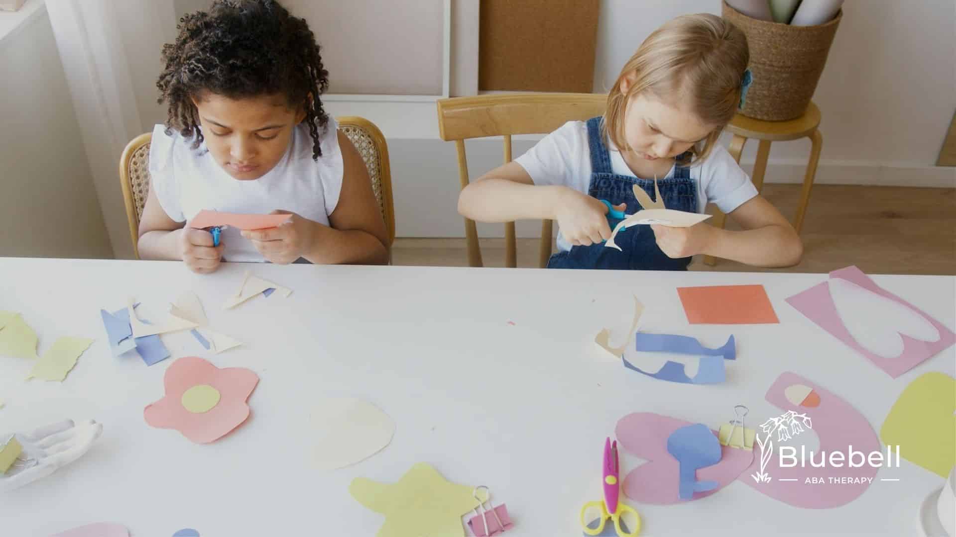 Autistic girls cutting colorful paper shapes during a craft activity at an ABA therapy center in NC.