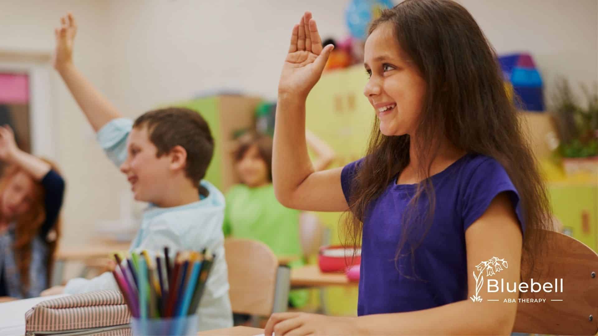 Autistic girl in a purple shirt raises her hand in a bright and colorful classroom.
