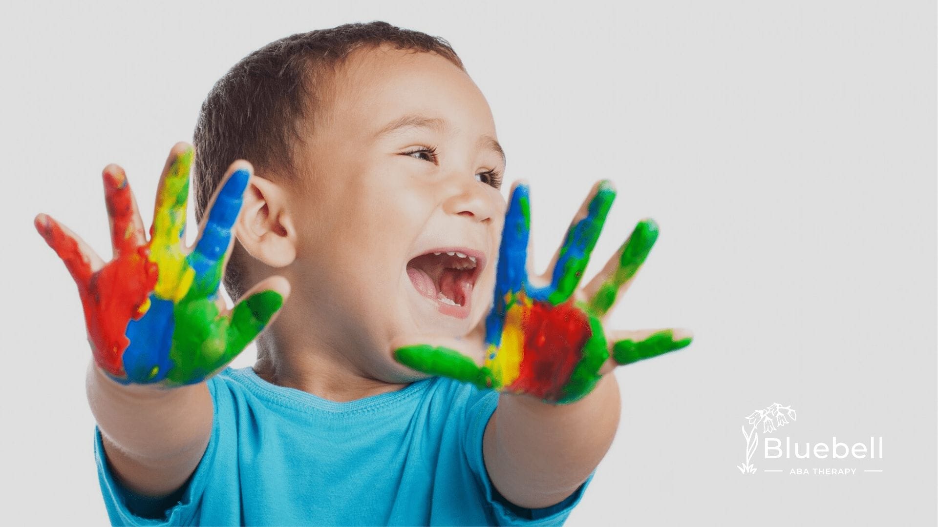 A neurodivergent kid holding his colored hands up