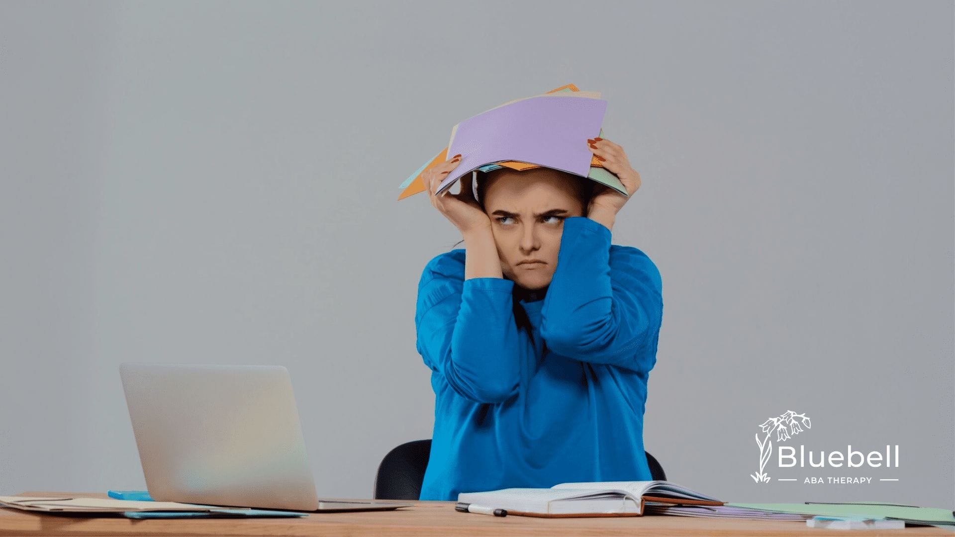 An adult with autism with a pile of papers on her head